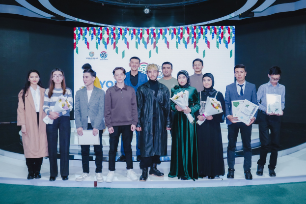 Gruppe von Menschen auf einer Bühne mit Blumensträußen und Urkunden, im Hintergrund ein "Youth Solar Awards 2019"-Plakat.