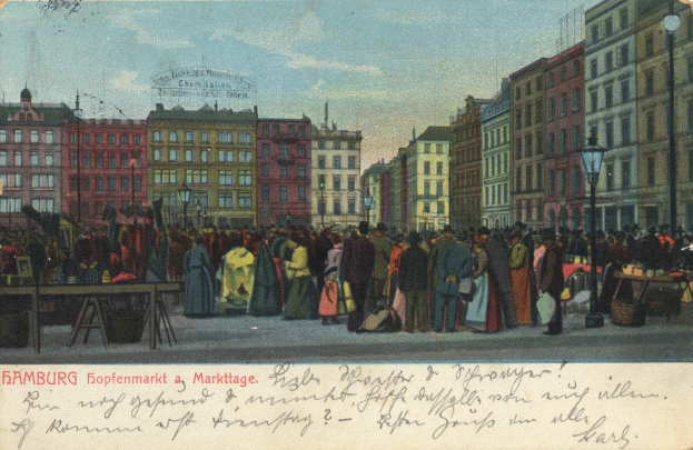 Schwarz-weiß-Postkarte eines belebten Hamburger Marktes mit Menschen, Tischen voller Waren, Straßenlaternen, Schildern, Gebäuden und einem bewölkten Himmel, mit Text unten.