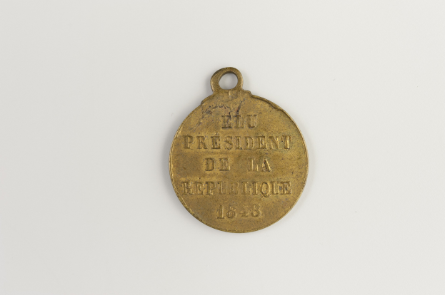 Goldmedaille mit 'Präsident der Republik' eingraviert, vor weißem Hintergrund.