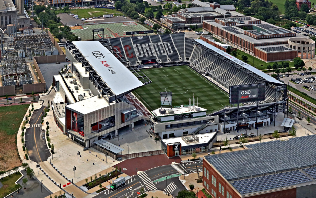 Luftaufnahme des Audi Field, dem Heimstadion des Atlanta United Football Club, umgeben von Stadtgebäuden, Bäumen, Straßen, Fahrzeugen, Polen und Gras.