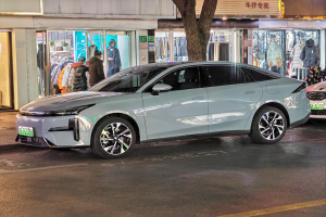 Ein Mitsubishi Lancer EV, der nachts auf einer Straße geparkt ist, umgeben von Gebäuden, Geschäften, Schaufensterpuppen, Schildern und Lichtern.