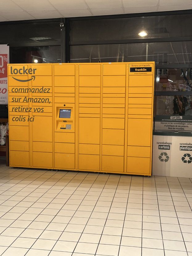 Ein gelber Spind mit Text darauf vor einer Glastür in einer U-Bahn-Station platziert, umgeben von verstreuten Kartonagen und anderen Gegenständen, mit Stationwänden im Hintergrund.