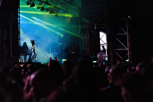 Ein volles Konzert mit Performern auf der Bühne, beleuchtet von Scheinwerfern vor einem dunklen Hintergrund.