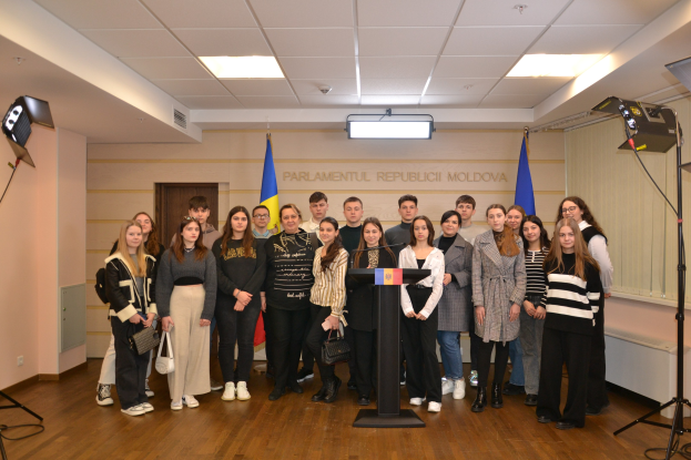 Gruppe von Menschen vor einem Rednerpult mit Mikrofon auf dem Moldova-Jugendkongress 2018, umgeben von Fahnen, einer Wand mit Text, einer Tür, Deckenleuchten und Stativen.