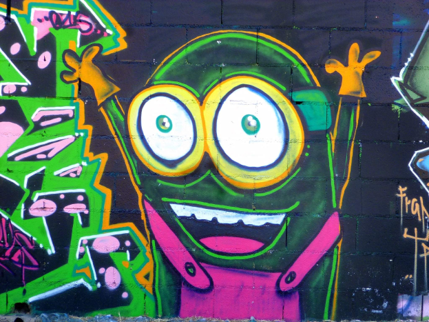 Buntfarbiger Cartoon-Graffiti-Charakter auf einer mit Graffiti bedeckten Wand gemalt.