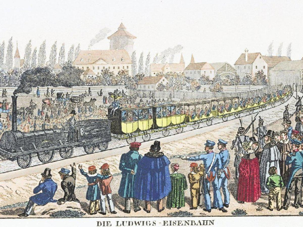 Eine Gruppe von Menschen um einen Zug auf einem Gleis herumstehend, mit einigen im Zug und anderen außerhalb, in der Nähe von Gebäuden und Bäumen, mit Text unten lesend "Ludwigs-Eisenbahn, die erste Bahnstation in Deutschland"