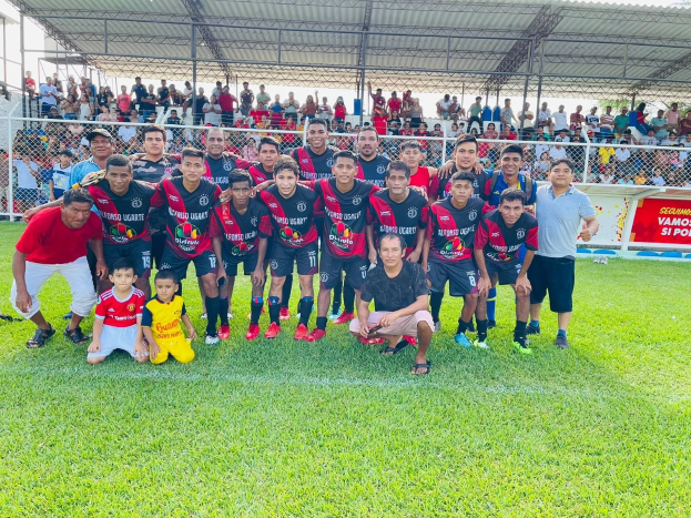 Eine Gruppe von Männern auf einem Fußballfeld, die eine Fahne mit der Aufschrift "Fotos Ugarte U-17 vs U-18" halten.