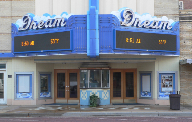 Außenansicht des Dream Theaters in St. Louis, Missouri, mit Glastüren, Fenstern, einer Namensplakette, einem Mülleimer, einem Topf mit einer Pflanze und einer Straße unten.