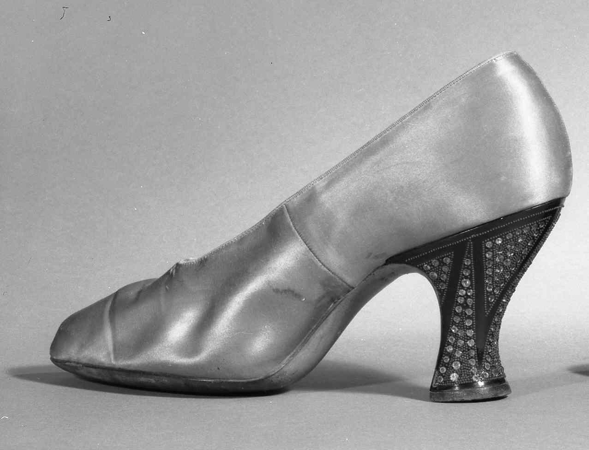 Schwarz-weiß-Foto eines Paares glänzender Frauen-High-Heels aus den 1930er Jahren.