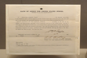 Ein Blatt mit dem Text "Eid für Bundesrichter der Vereinigten Staaten" liegt auf einem Tisch vor einer Wand.