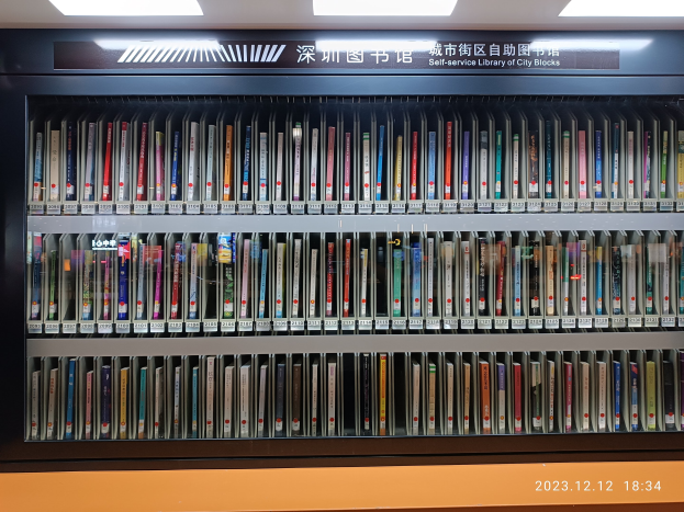 Eine gut beleuchtete Bibliothek mit hohen Bücherregalen voller Bücher, mit einer Texttafel und einem Wasserzeichen unten, ähnelt einer Selbstbedienungsbibliothek von Stadtblöcken.