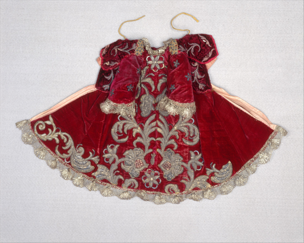 Ein rotes Samtkleid mit goldener Stickerei und detaillierten Designs auf einem Hanger gegen einen weißen Hintergrund.